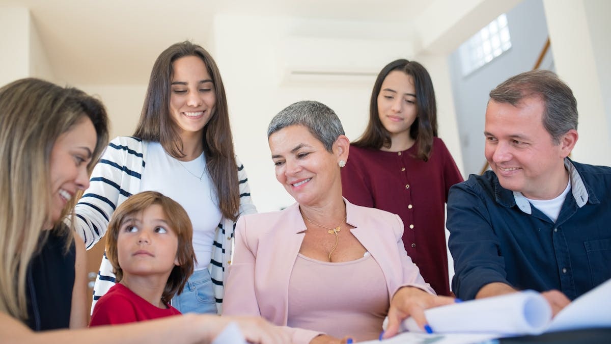 A family gathering around a table, discussing real estate documents indoors with a realtor.